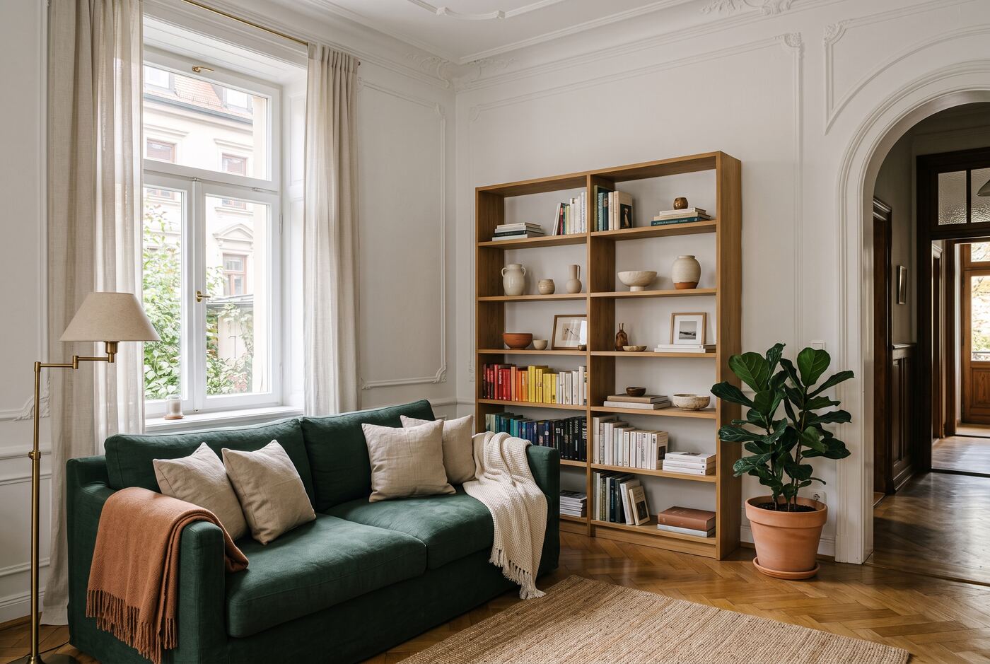 A serene organized living room with a pine green sofa and oak shelving